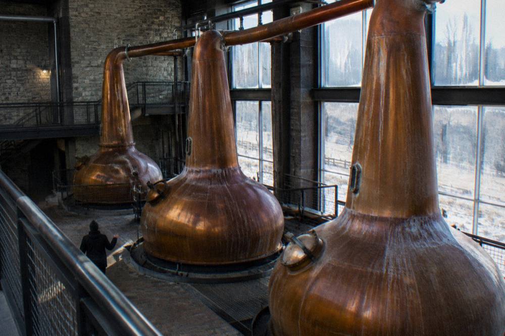 A copper pot still inside a Kentucky distillery tour stop with guided walkway railings