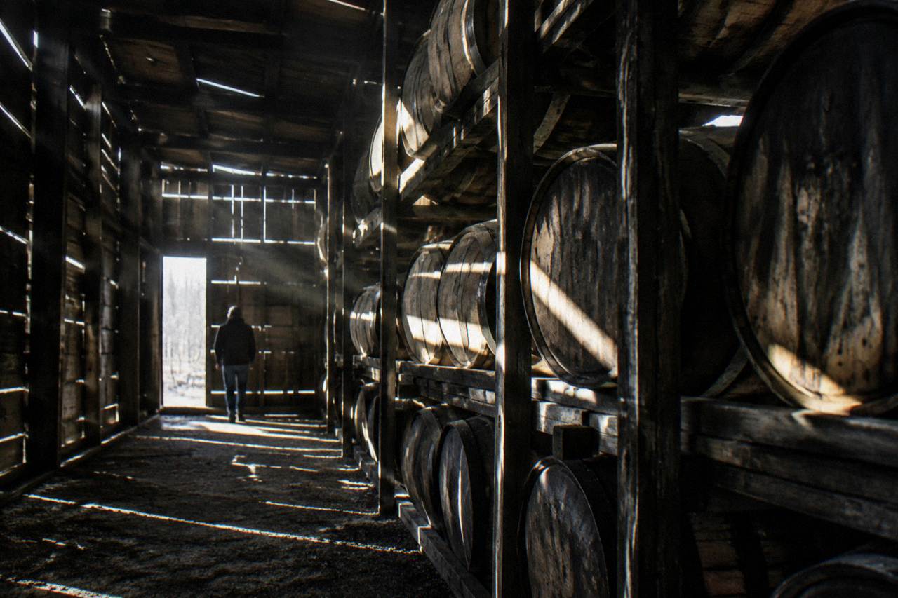 Row of bourbon barrels stacked in a Kentucky rickhouse with sunlight through wooden slats