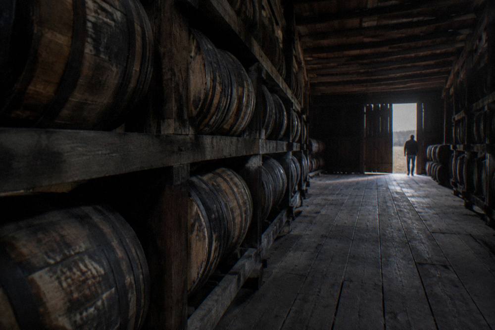 Row of bourbon barrels stacked inside a wooden rickhouse in Kentucky