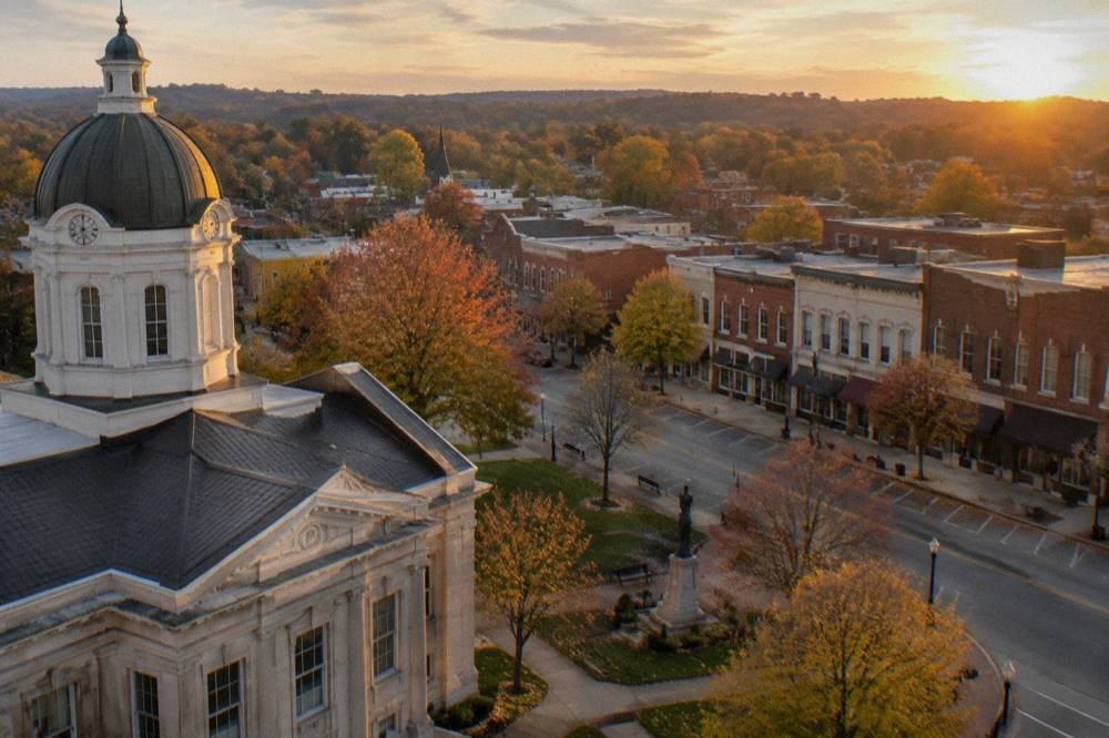 Courthouse square in a small Kentucky bourbon town at golden hour with parked cars and brick facades