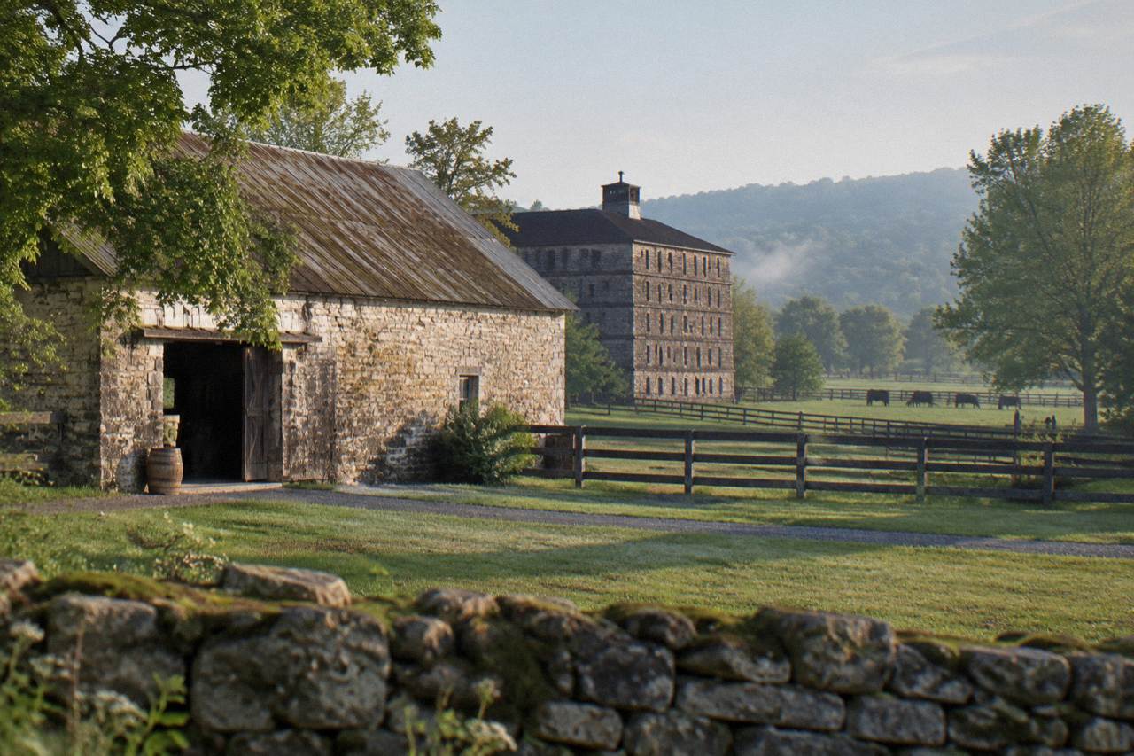 Rolling Kentucky farmland with limestone barns and a rickhouse in the distance