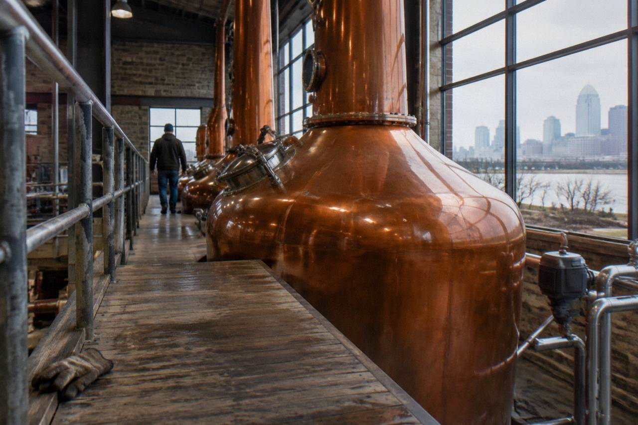 A wooden distillery walkway beside copper stills on a production floor in Kentucky