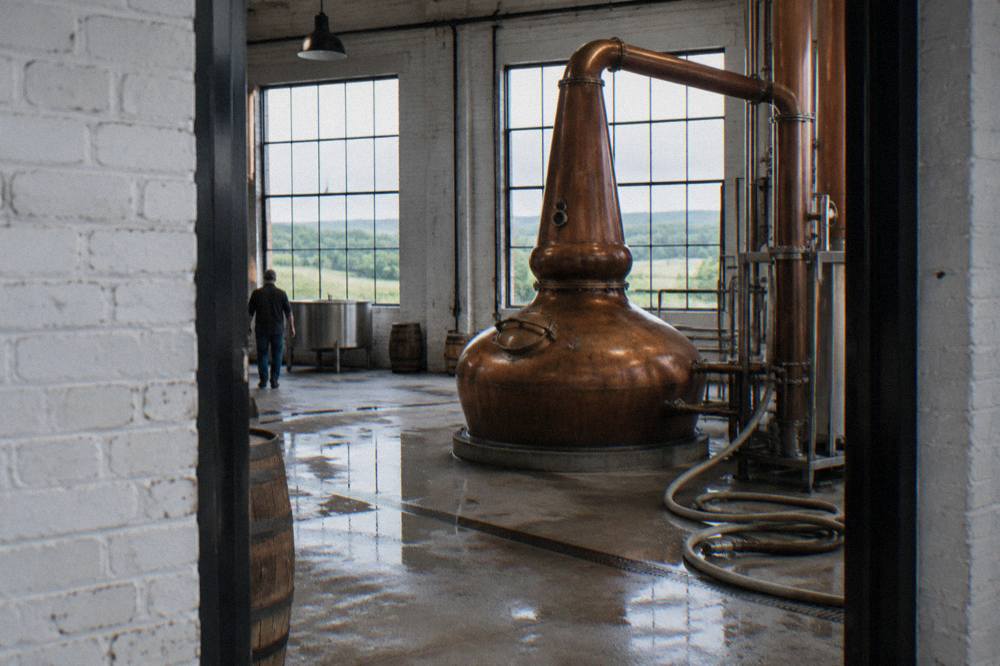 A copper pot still inside a bourbon distillery fermentation hall