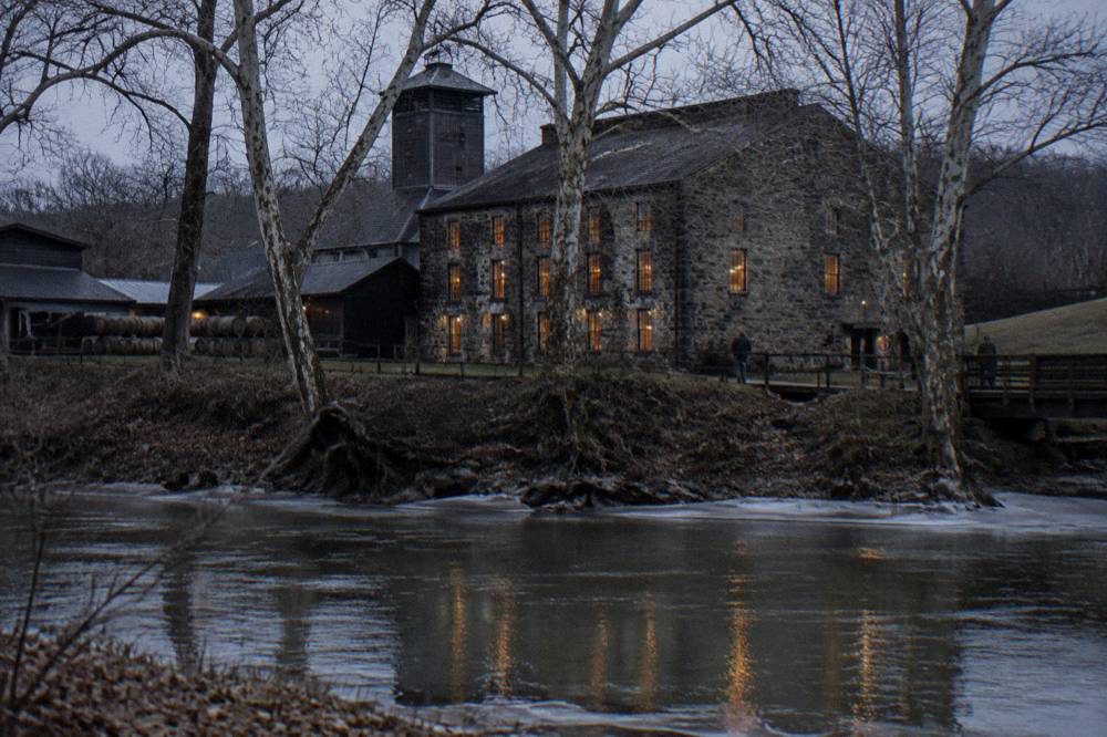 Stone distillery building beside the Kentucky River at dusk