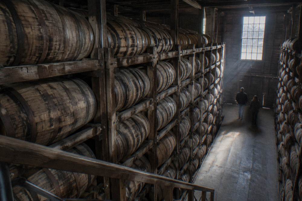 Rows of oak bourbon barrels resting in a dim warehouse