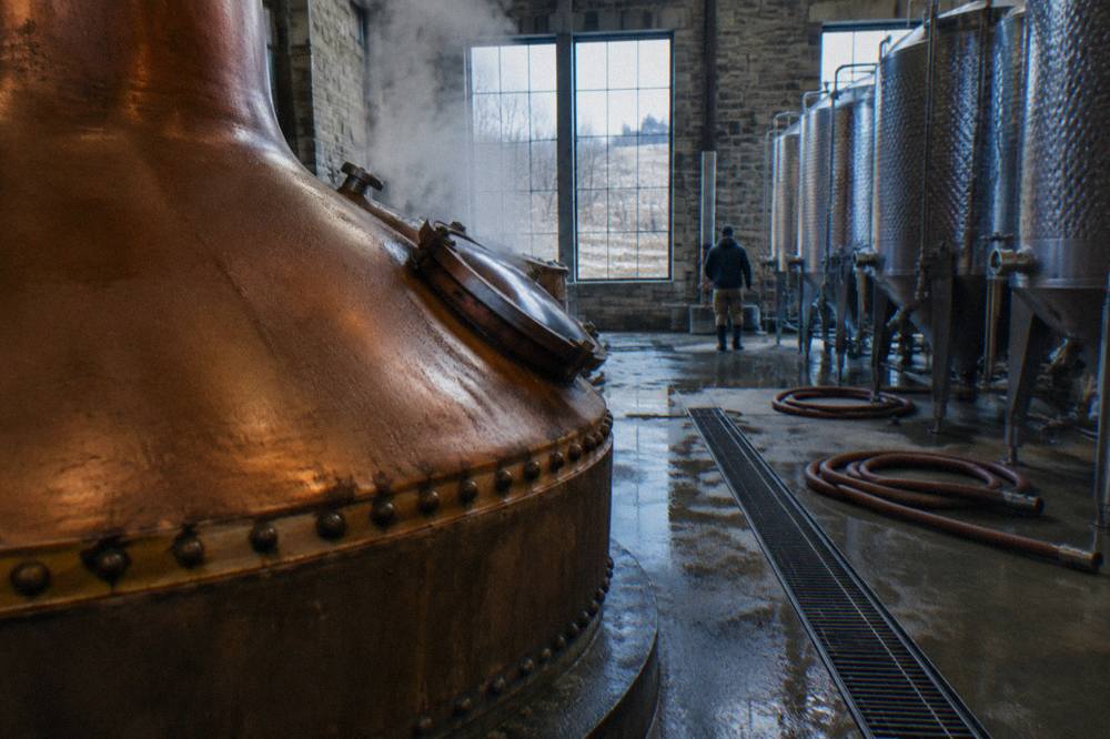 Copper still and fermentation tanks inside a working bourbon distillery