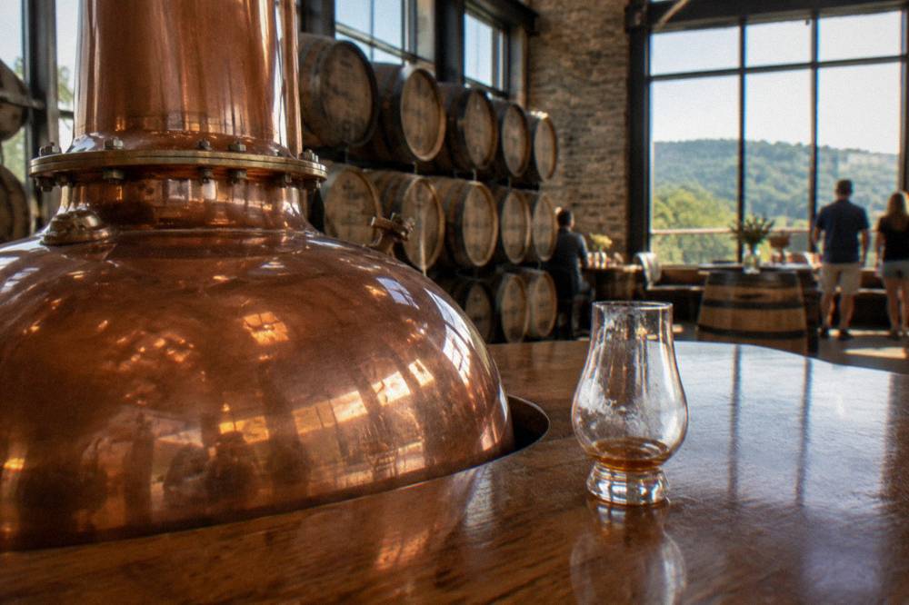 Sunlit visitor center tasting room with copper fixtures and oak barrels
