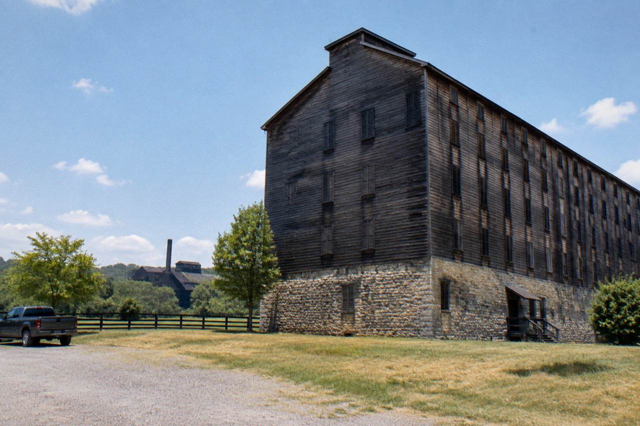 Wooden rickhouse exterior with limestone walls under a wide Kentucky sky