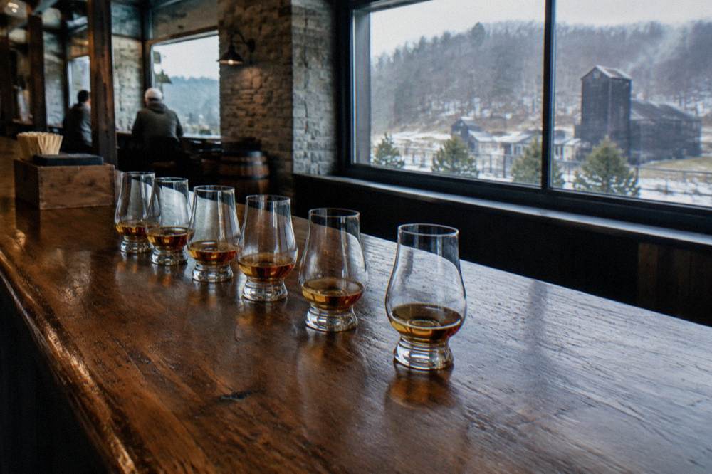 Long wooden tasting bar with bourbon glasses lined up before a guided tasting