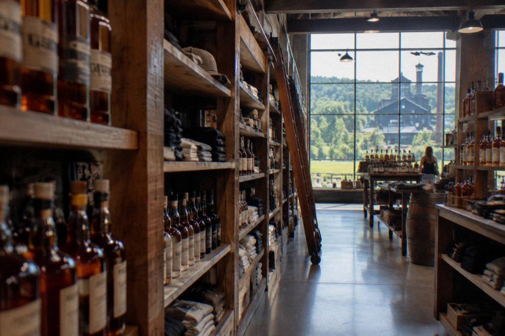 Distillery gift shop shelves stacked with bourbon bottles and merchandise