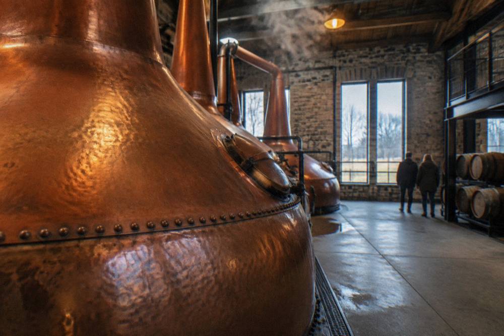 A copper pot still inside a lit distillery hall in Kentucky