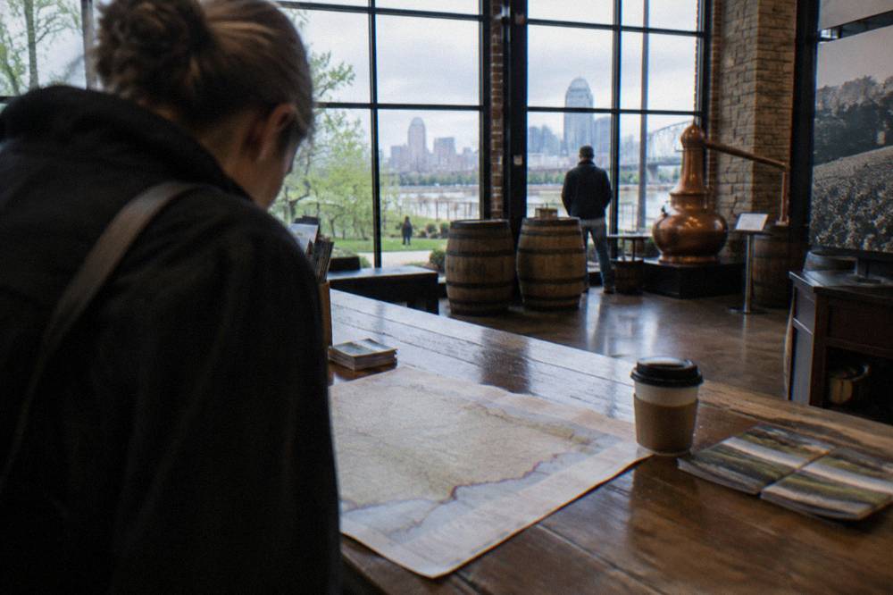 A visitor reading a printed Kentucky map at a distillery welcome center desk
