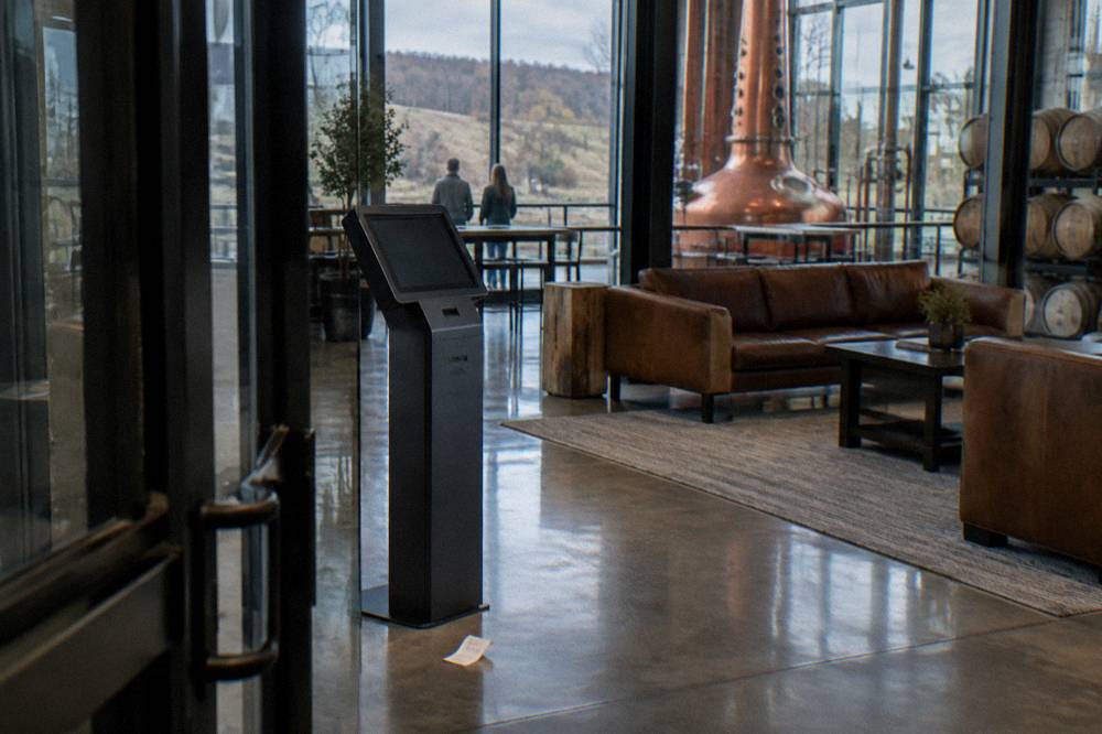A booking kiosk and seating area inside a modern distillery visitor center