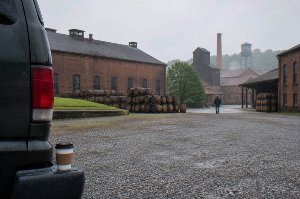 A passenger van parked outside a distillery with brick warehouse buildings in the background