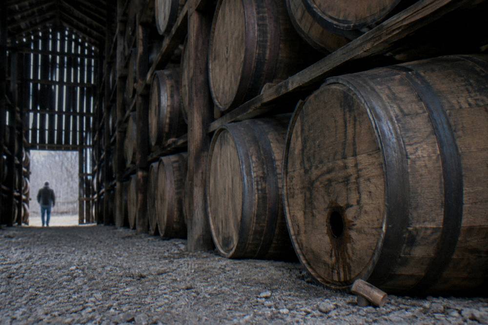 Rows of bourbon barrels resting in a dark Kentucky rickhouse