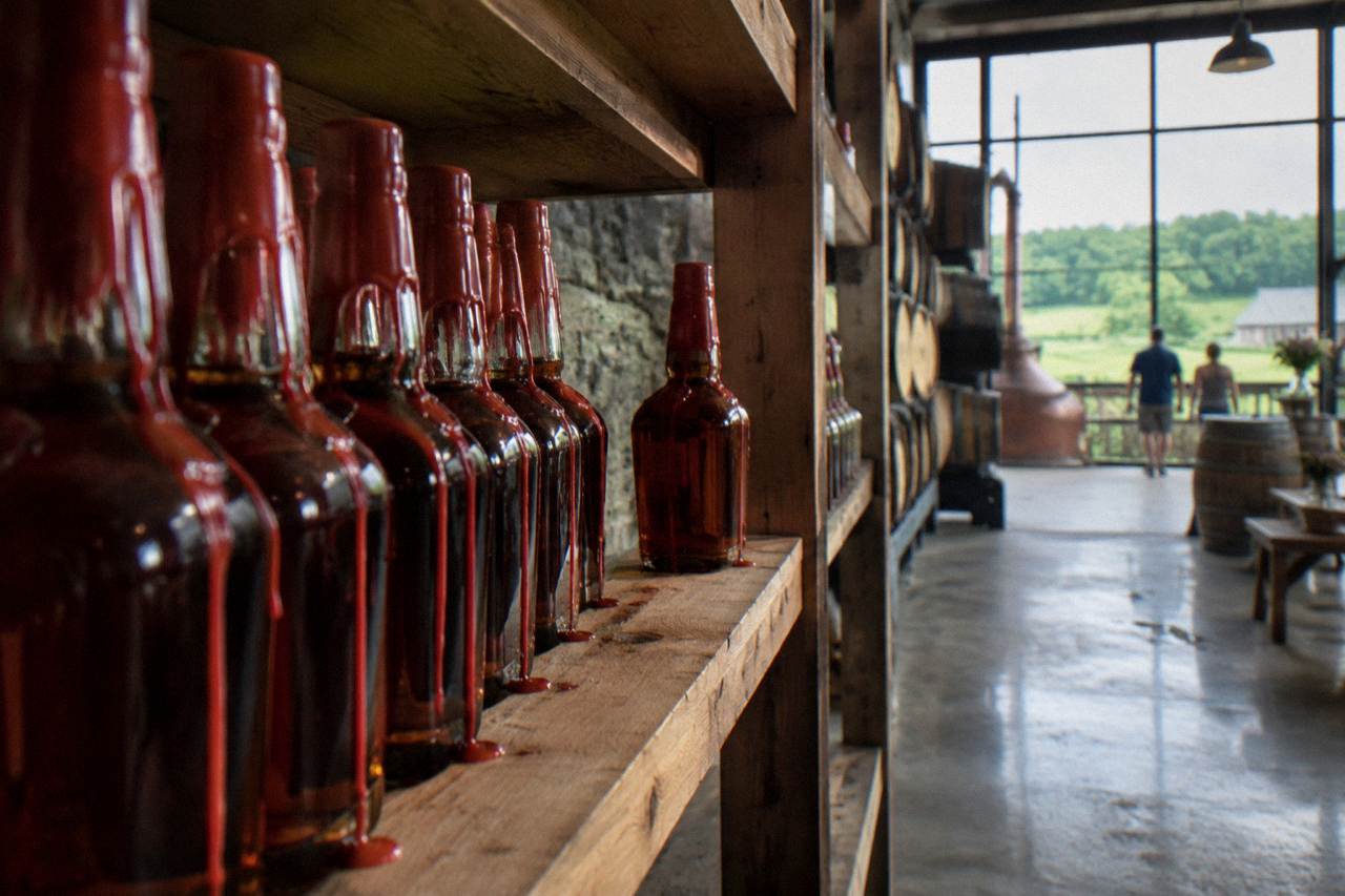 Red wax-dipped bourbon bottles lined up on a wooden distillery shelf