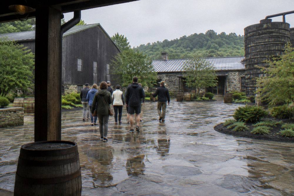 Small tour group walking with a guide across a distillery courtyard